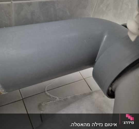 צינור אפור עם חיבורי אינסטלציה על רצפת קרמיקה